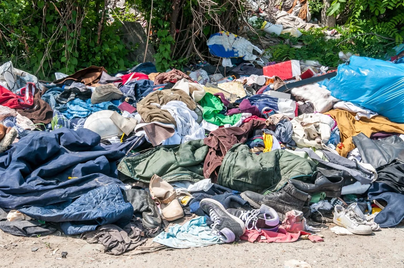 Piles of discarded clothing in a landfill, showing the environmental impact of fast fashion.
