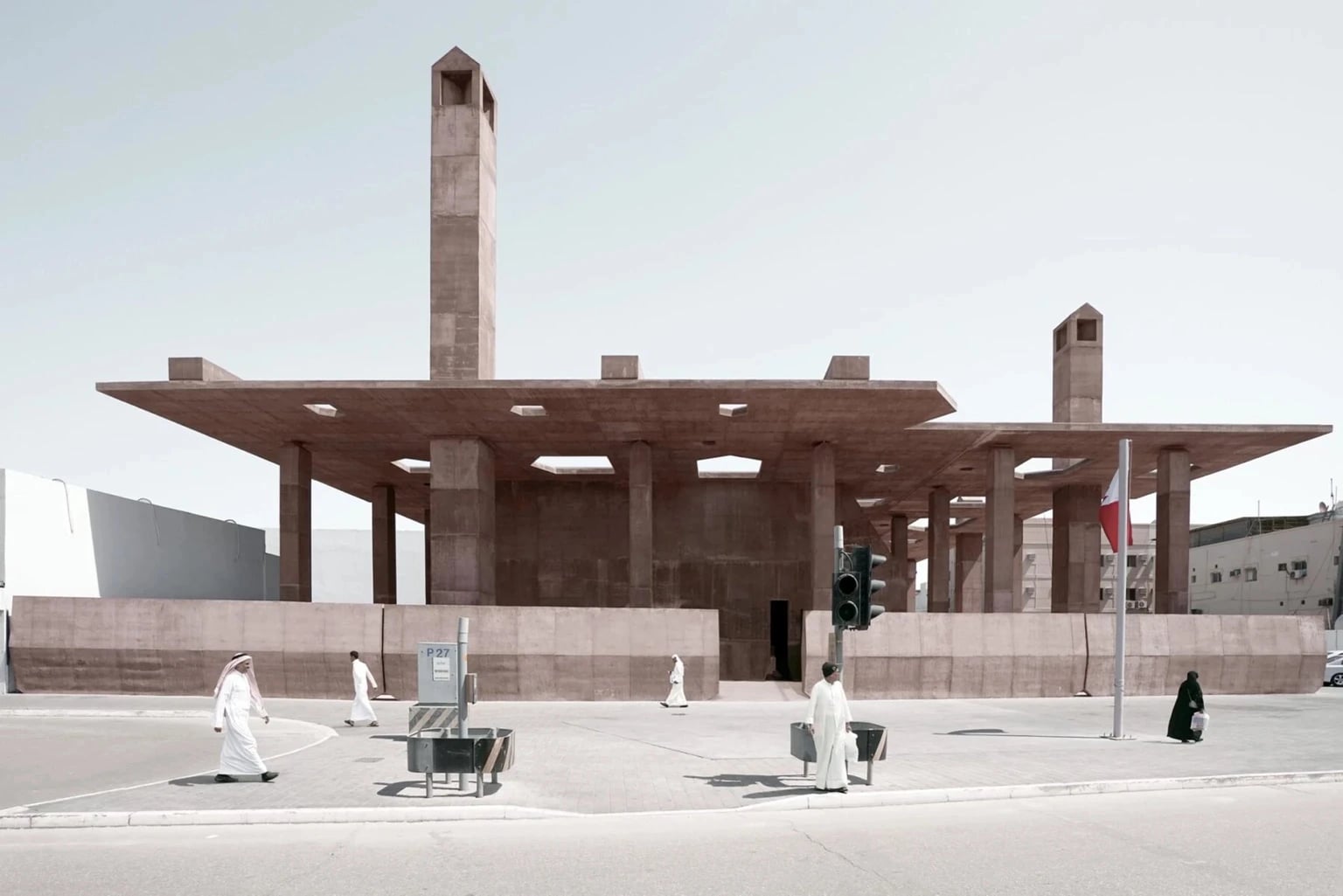Pearling Path Visitor Centre in Muharraq, Bahrain – minimalist concrete building with tall columns and a wide flat roof, designed by Valerio Olgiati, with people in traditional dress walking in the foreground.