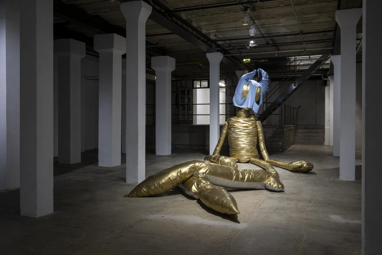 Installation view of Takapau by Mataaho Collective at La Biennale di Venezia, featuring woven polyester tie-downs and metal fittings suspended within a brick-columned exhibition space.